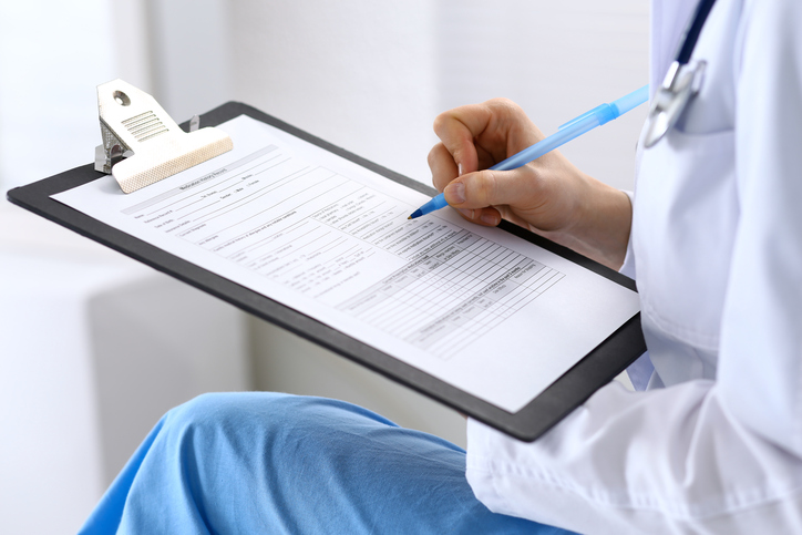 Female doctor filling up medical form on clipboard closeup. Physician finishing up examining his patient in hospital and ready to give a prescription to help. Healthcare, insurance and medicine concept.