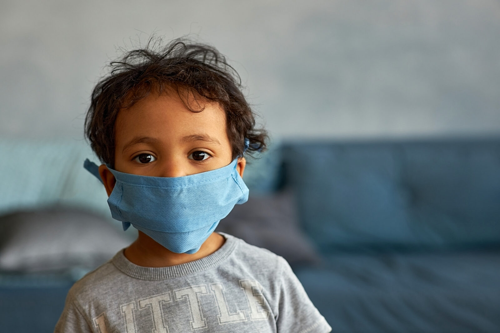 Portrait of a cute african american boy in mask at home - contagion of the Novel Coronavirus 2019- ncov - virus incubation isolation