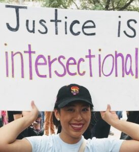 Peggy Li is holding up a sign that says "Justice is intersectional"