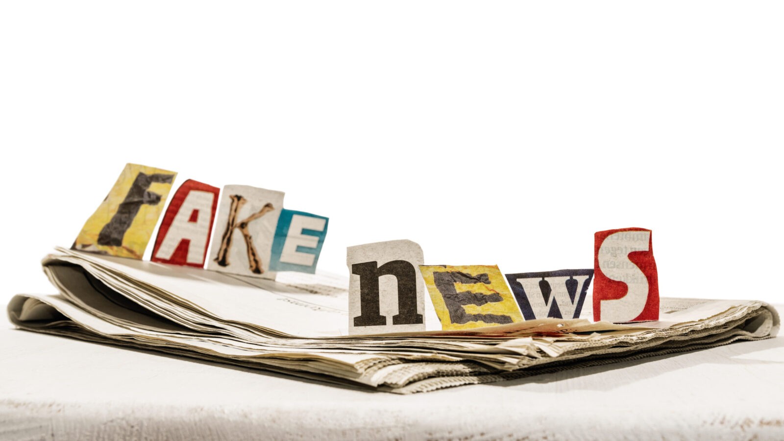 cut out letters spelling fake news on top of a folded newspaper