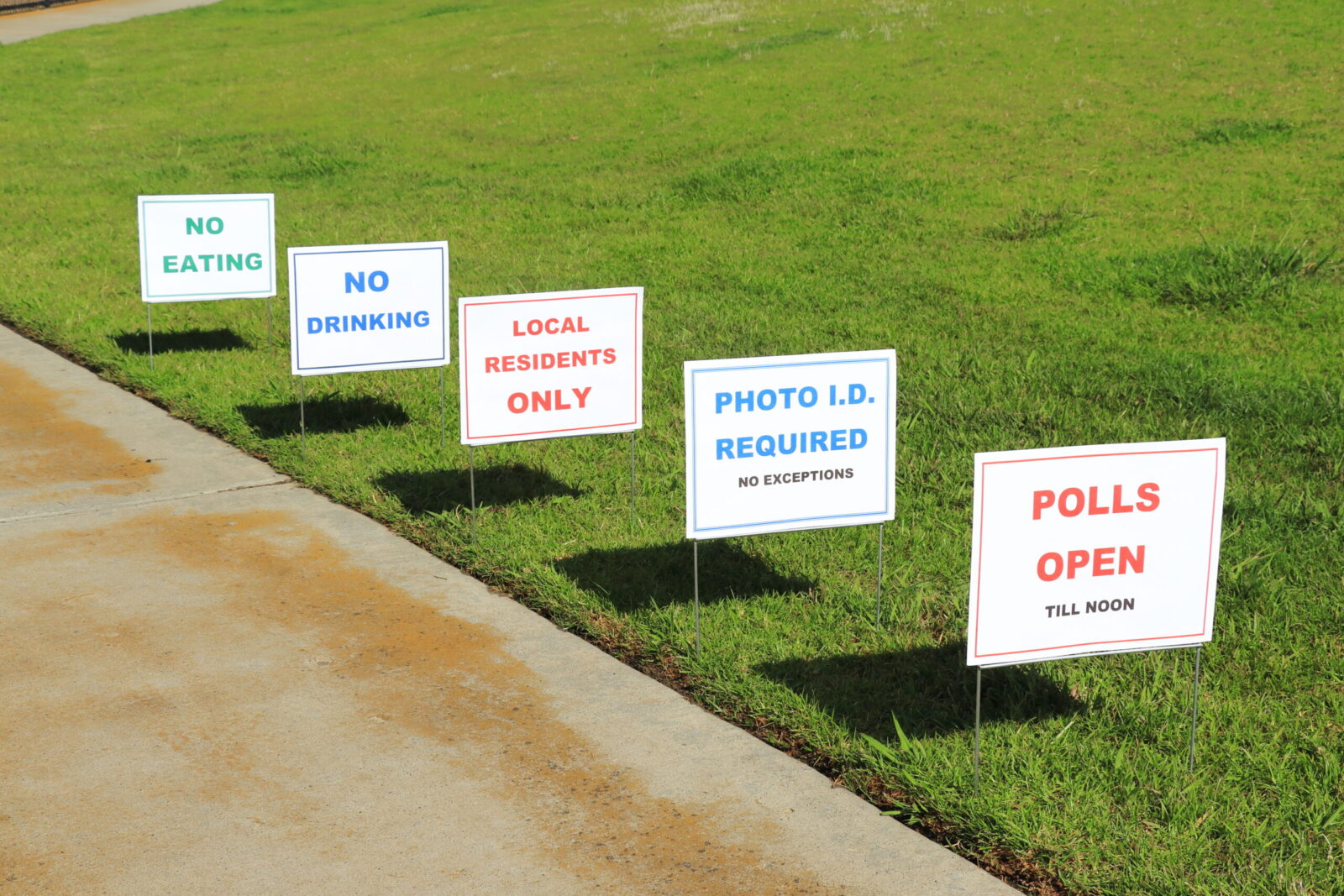 successive signs on grass leading to the polling place with restrictions