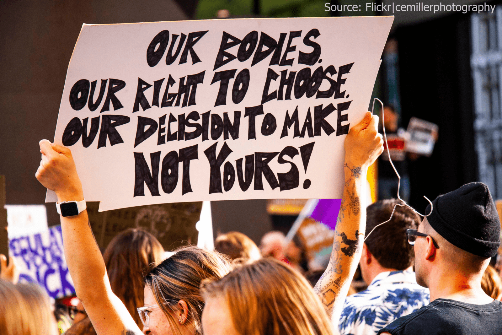 image from reproductive rights rally in Chicago in 2019 of a woman holding a sign that says "our bodies our right to choose our decision to make not yours!"