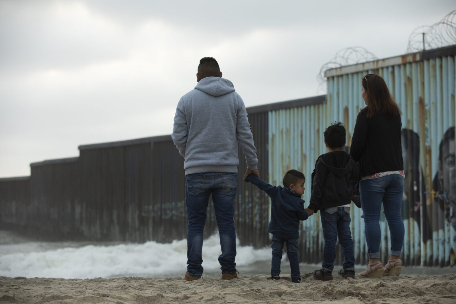 Tijuana, Baja California, Mexico - April 11, 2021: A family stands in front of the USA Mexico border wall.