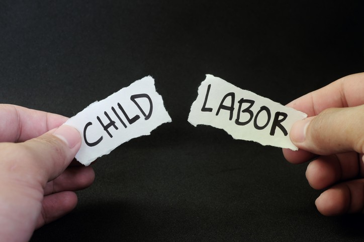 Stop and fight child labor concept. Human hand tearing a piece paper with written word child labor. Children rights protection.