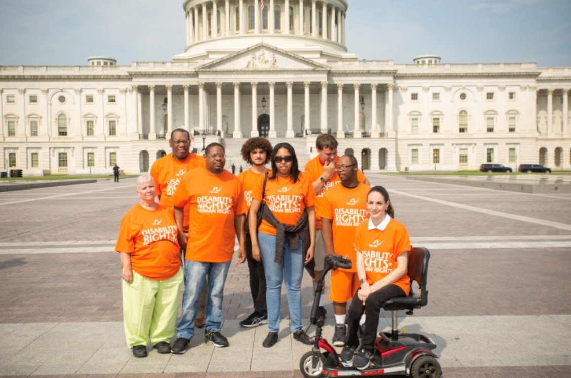 Disabaility advocates wearing orange stand in front of US Capitol building