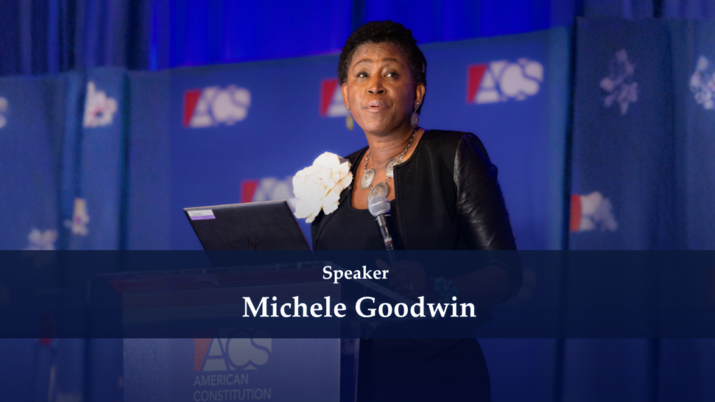 Female speaker at a podium delivering a talk on a blue-stage backdrop with ACS logos visible in the background.