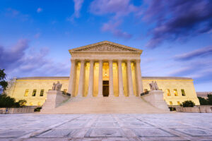 U.S. Supreme Court building with illuminated columns and grand staircase at dusk.